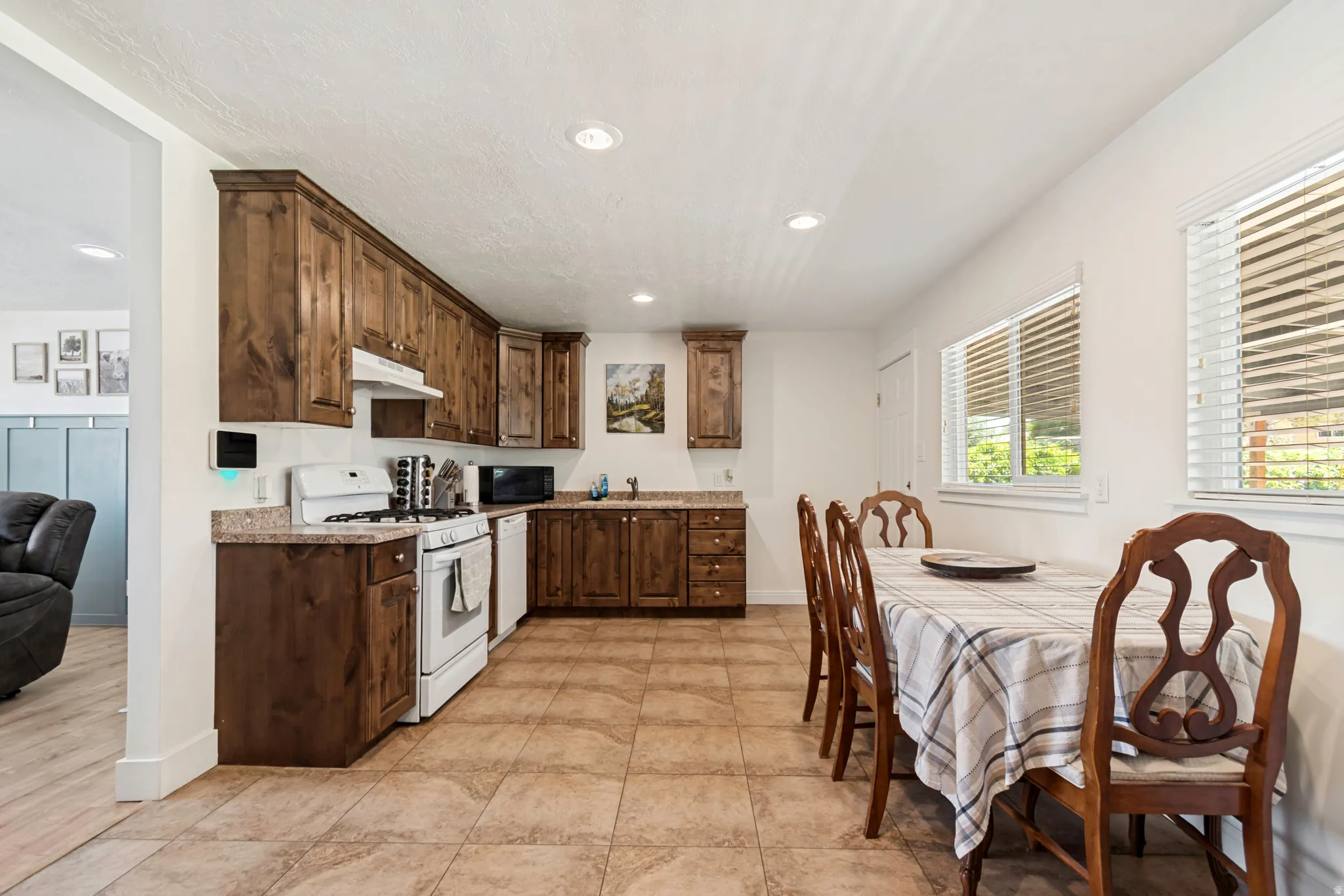 Kitchen and dining area featuring wood cabinetry, light-toned countertops, and tile flooring
