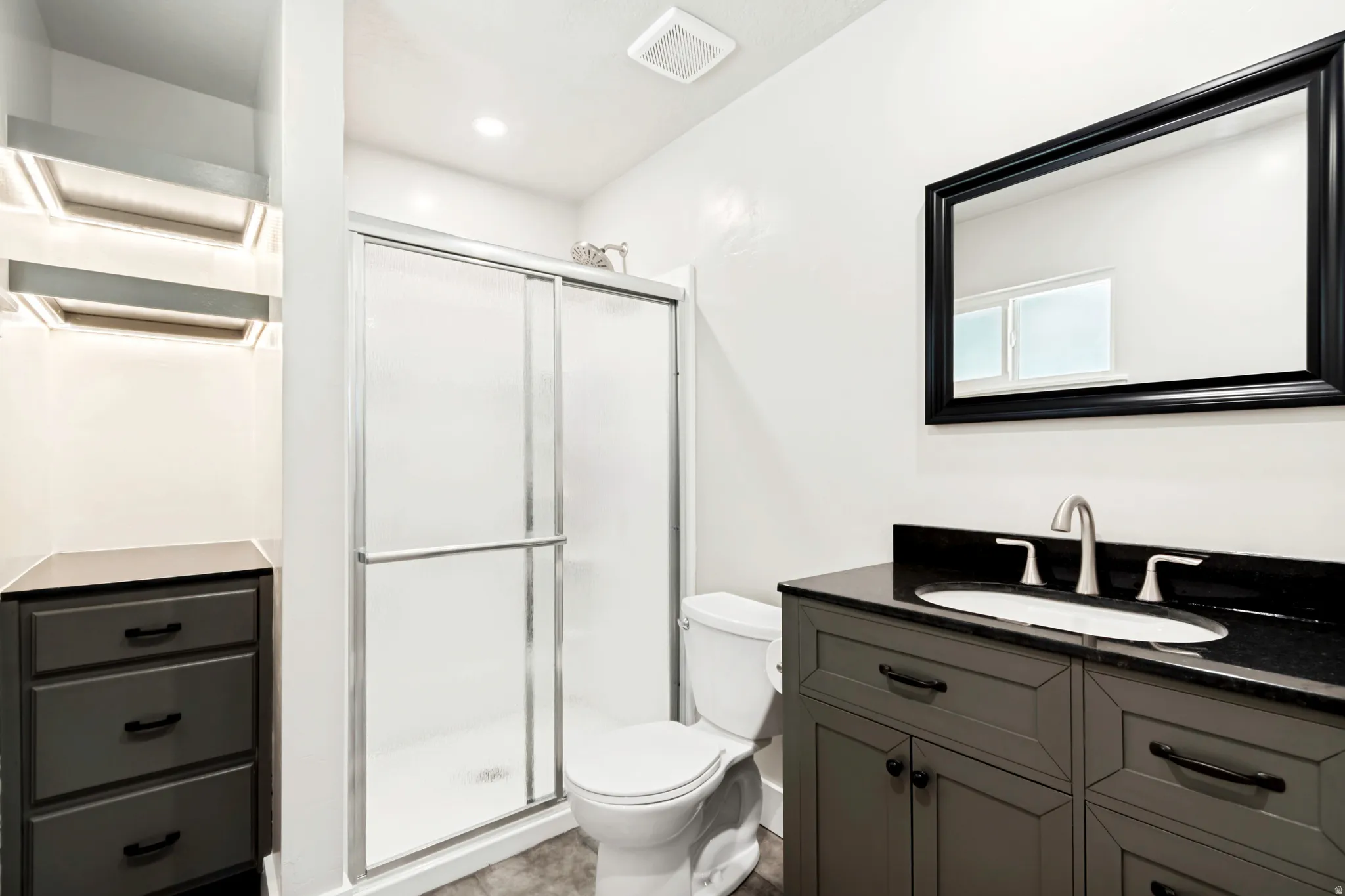Bathroom featuring a dark gray vanity with a black countertop, an undermount sink, and a brushed nickel faucet newly remodled