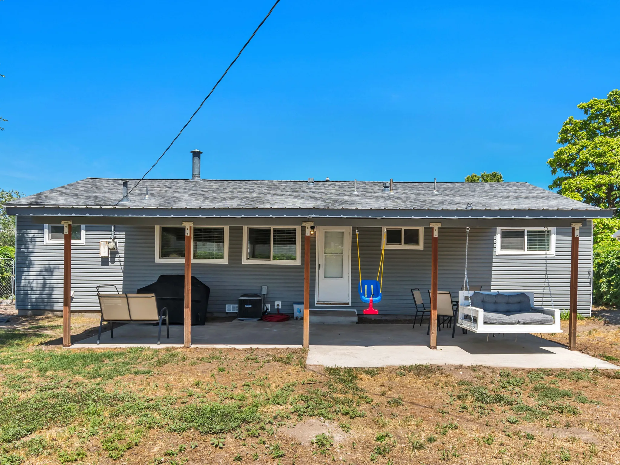 Rear exterior featuring gray horizontal siding and a covered concrete patio