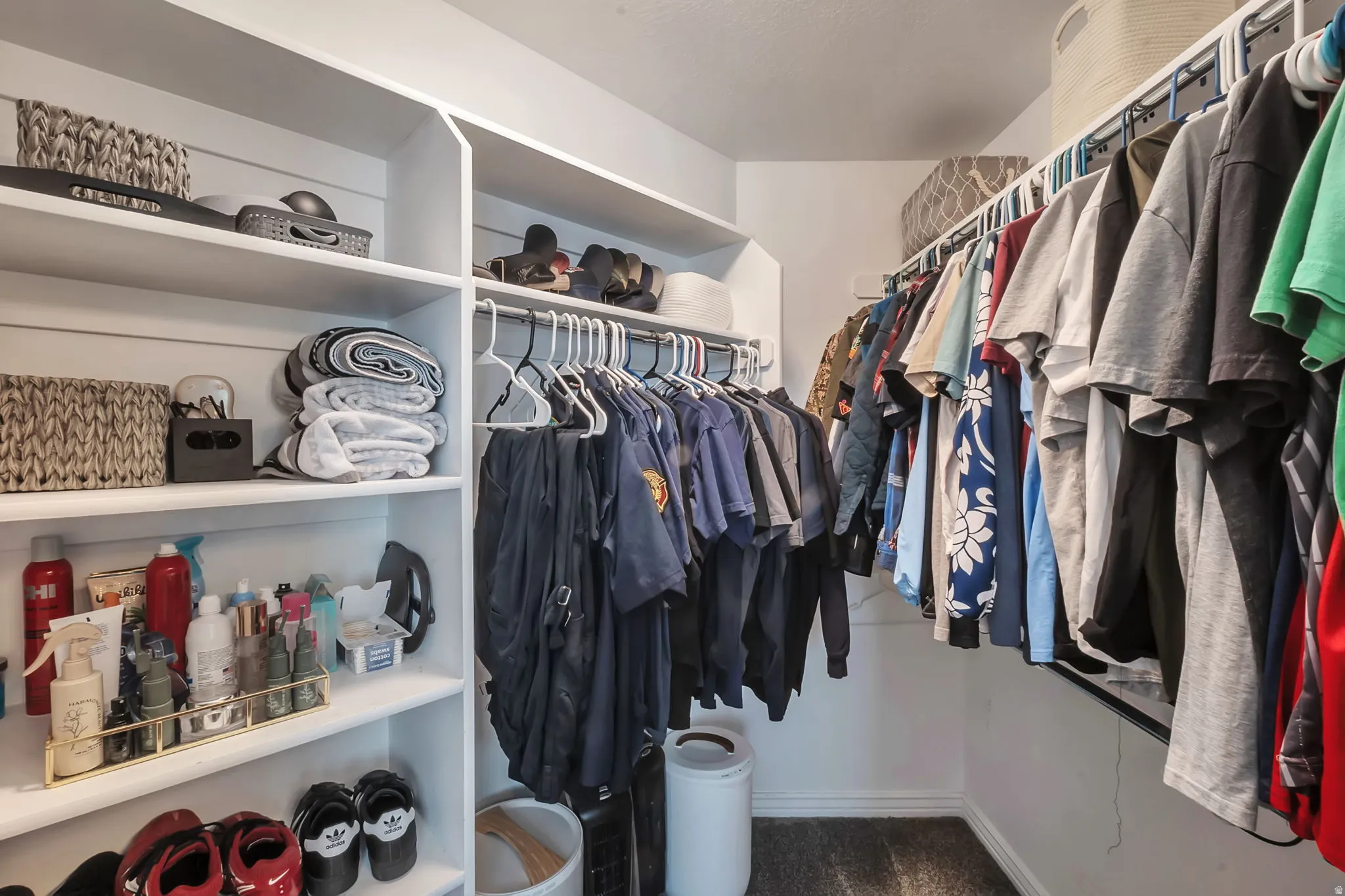 Walk-in closet featuring white built-in shelving, multiple hanging rods, and a carpeted floor