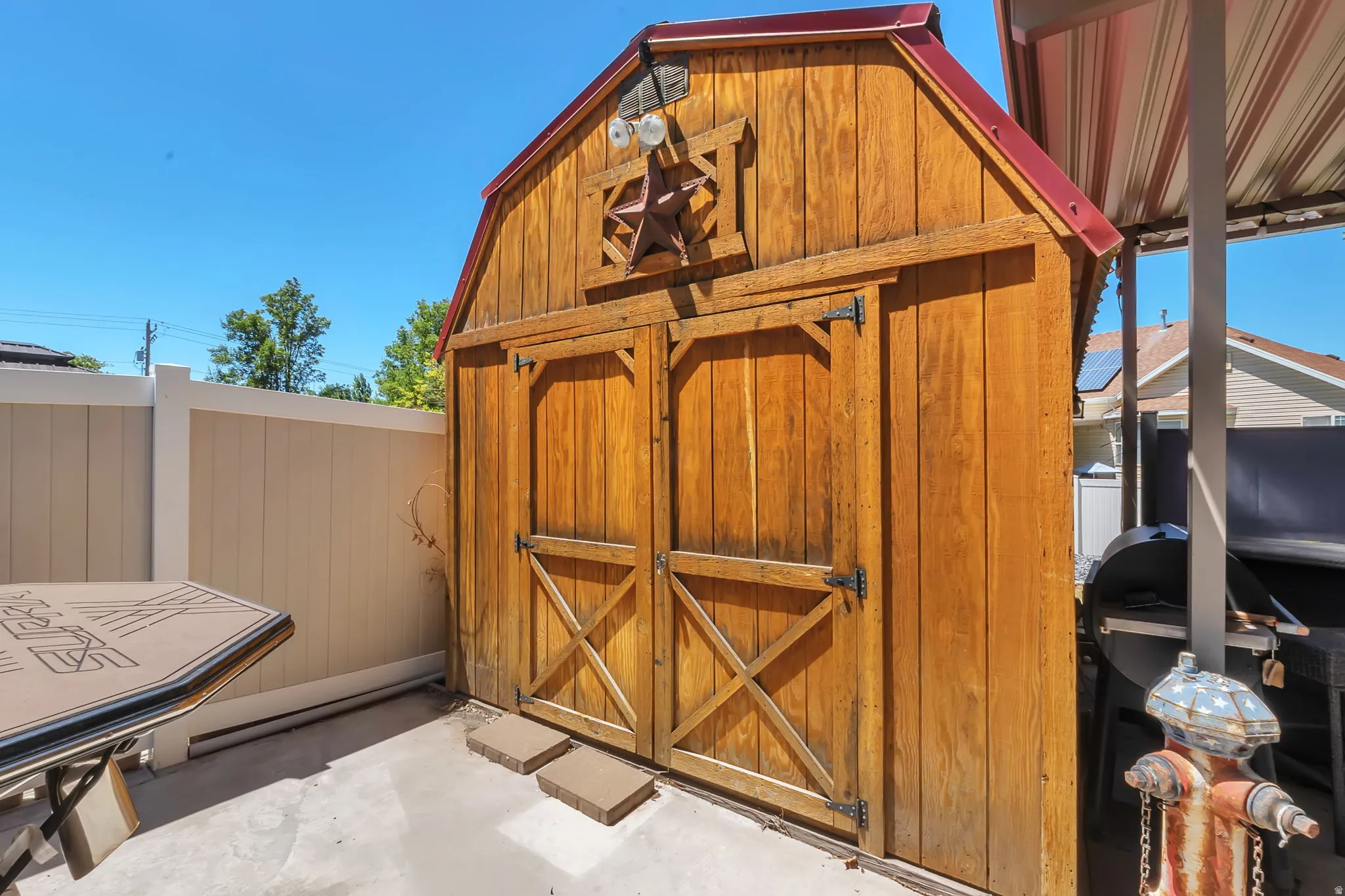 Barn-style wooden shed with a red metal roof and double doors