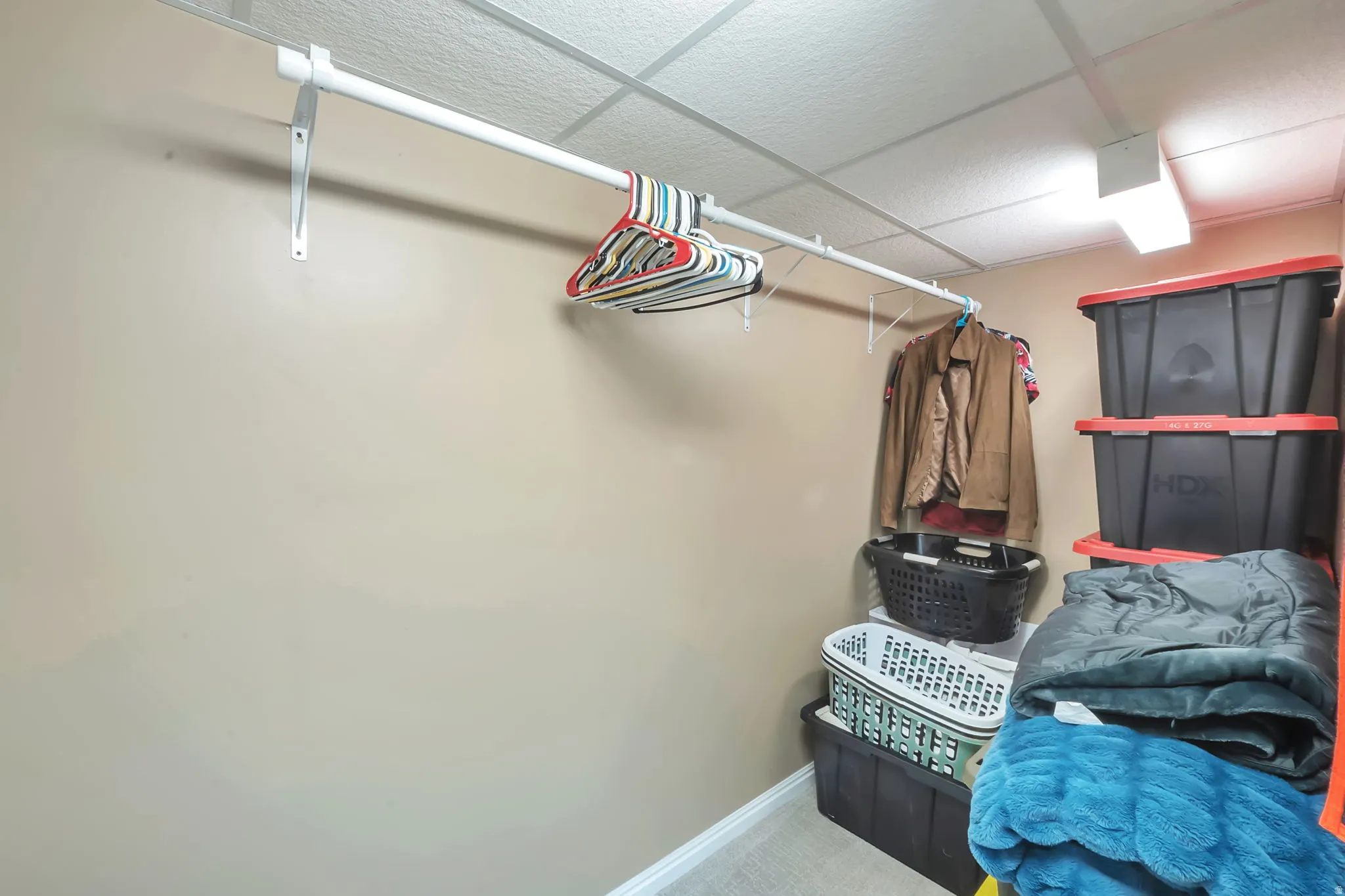 Integrated clothes hanging rod, drop ceiling, recessed lighting fixture, carpeted flooring, and neutral wall paint
