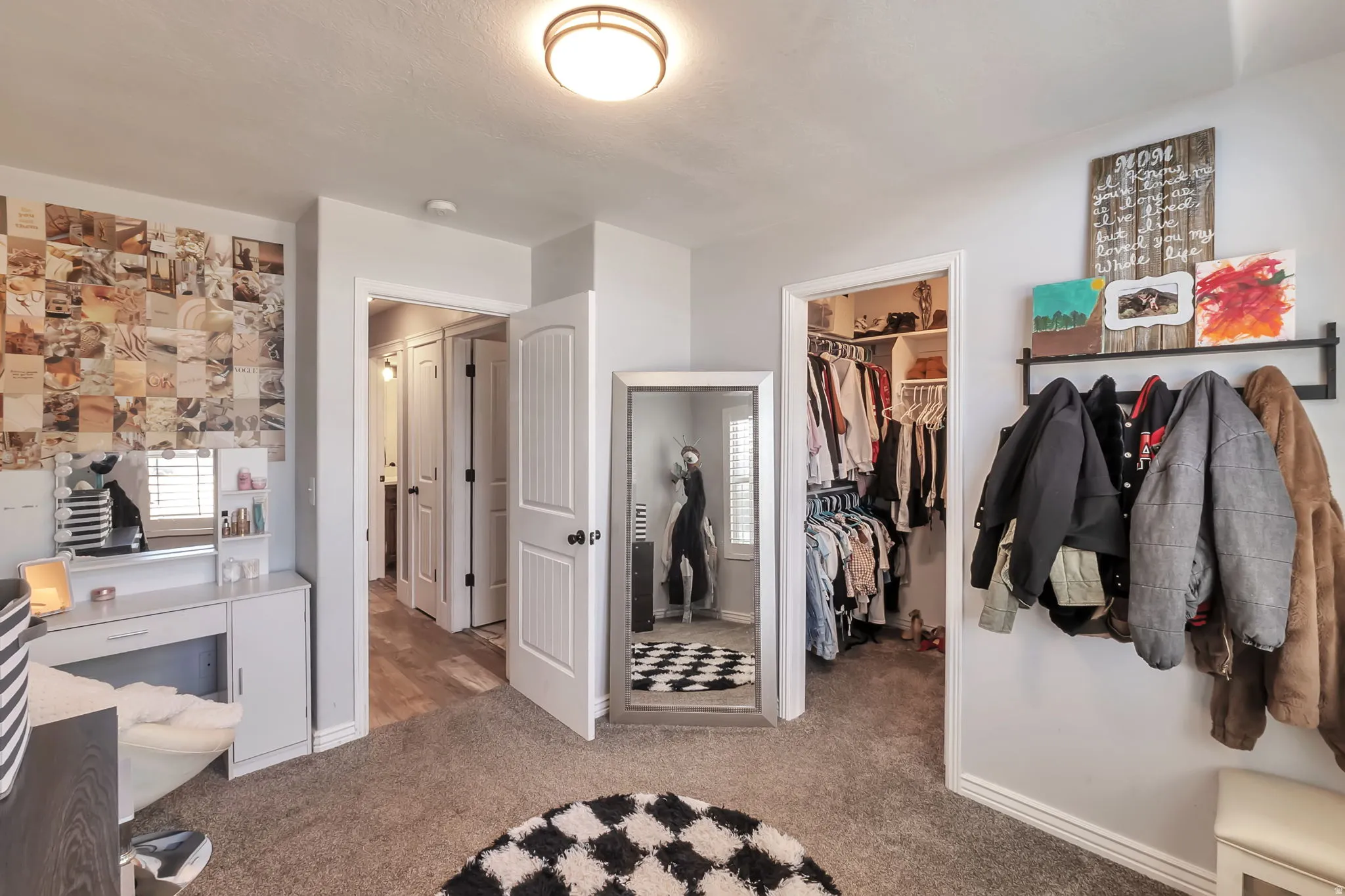 Carpeted interior room featuring a built-in closet with shelving, a white paneled door, and a flush-mount ceiling light fixture