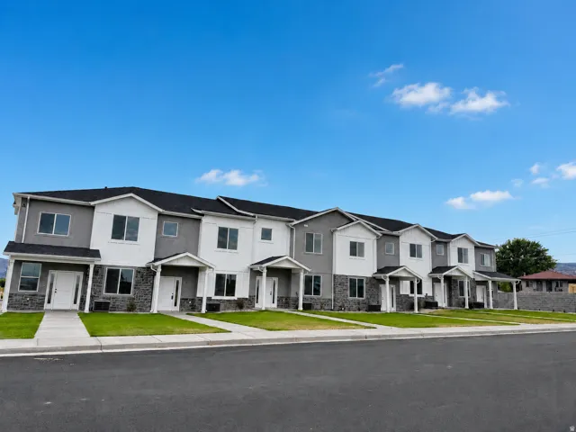 Contemporary multi-unit residences featuring dark asphalt shingle roofs, light stucco siding, and stone veneer accents