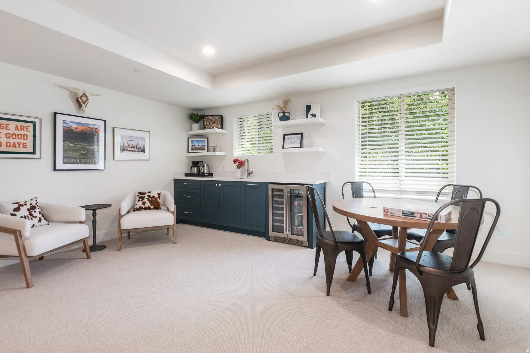 Functional living area featuring soft neutral carpeting, recessed ceiling lighting, a built-in wet bar with dark cabinetry and a beverage refrigerator, and a window with horizontal blinds