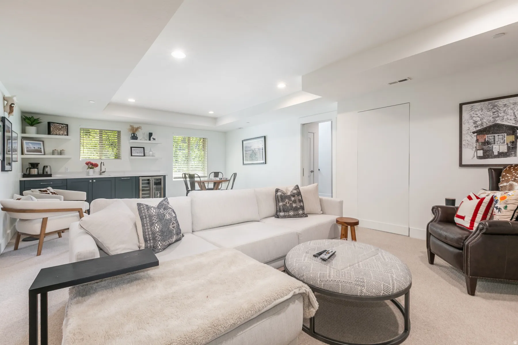 Lower-level entertainment space featuring recessed lighting, light-toned carpeting, and a built-in wet bar with dark cabinetry, a beverage refrigerator, and open shelving