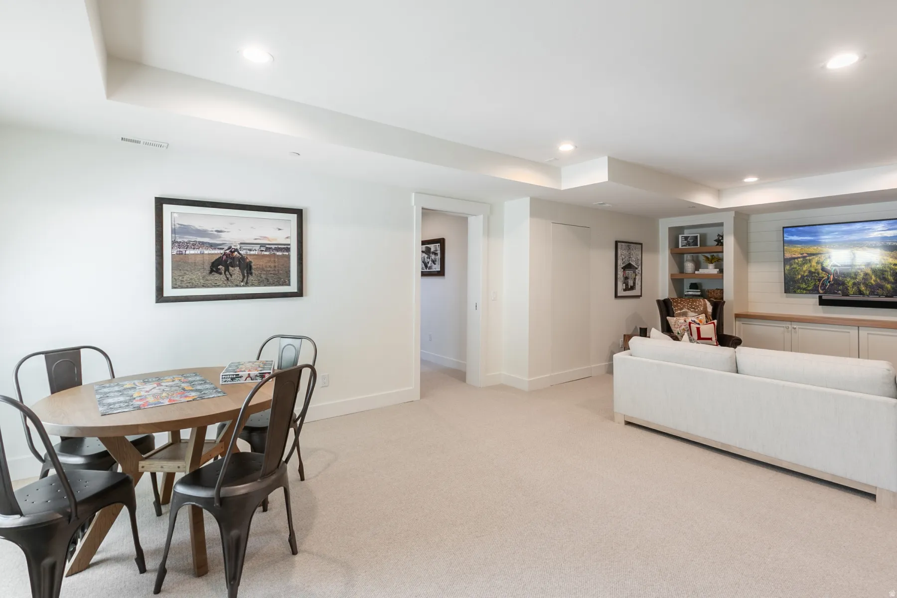 Expansive carpeted room featuring recessed lighting, a tray ceiling detail, built-in shelving, and custom cabinetry with shiplap accents