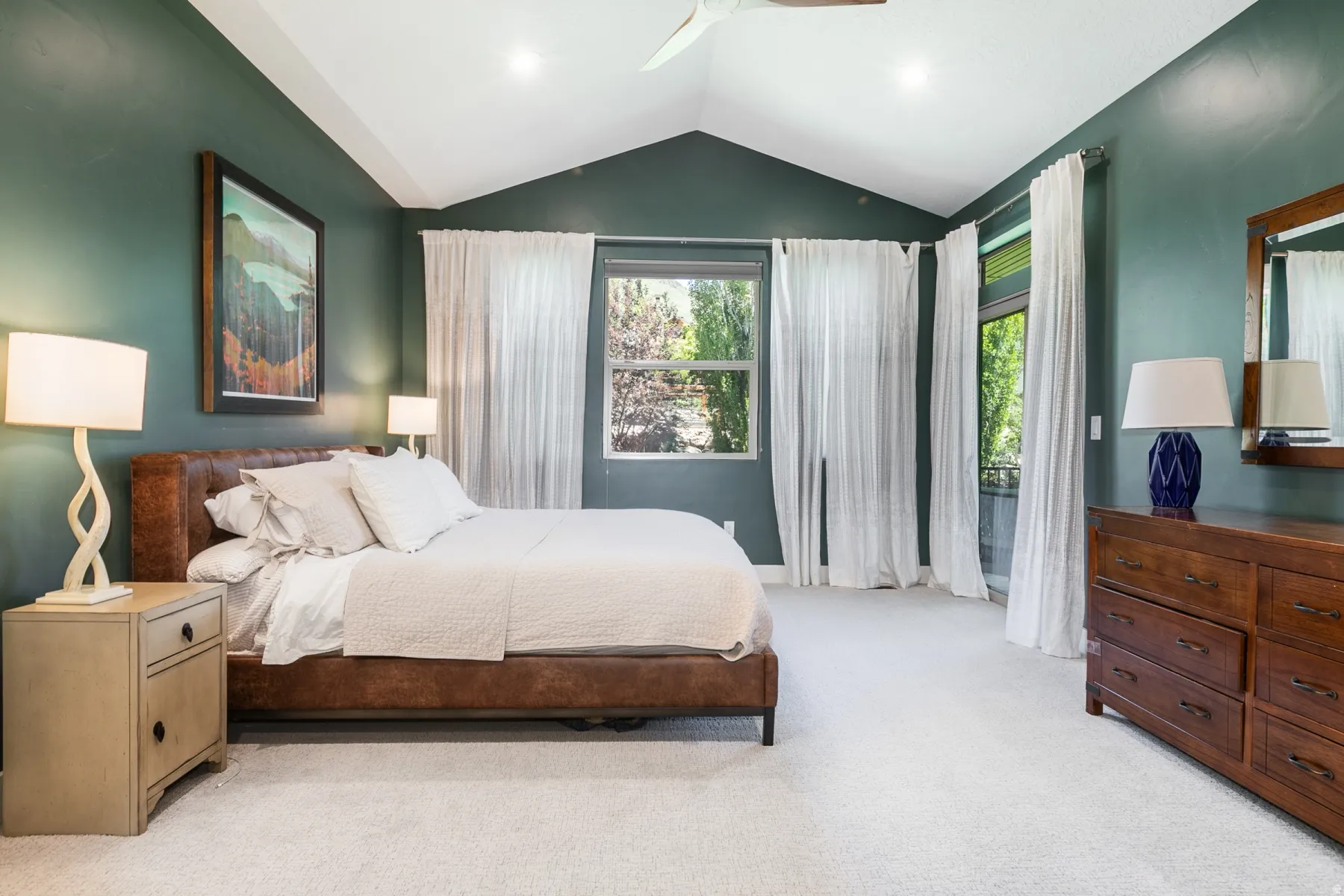 Spacious room with vaulted ceilings, recessed lighting, a large window, and a glass-paneled door