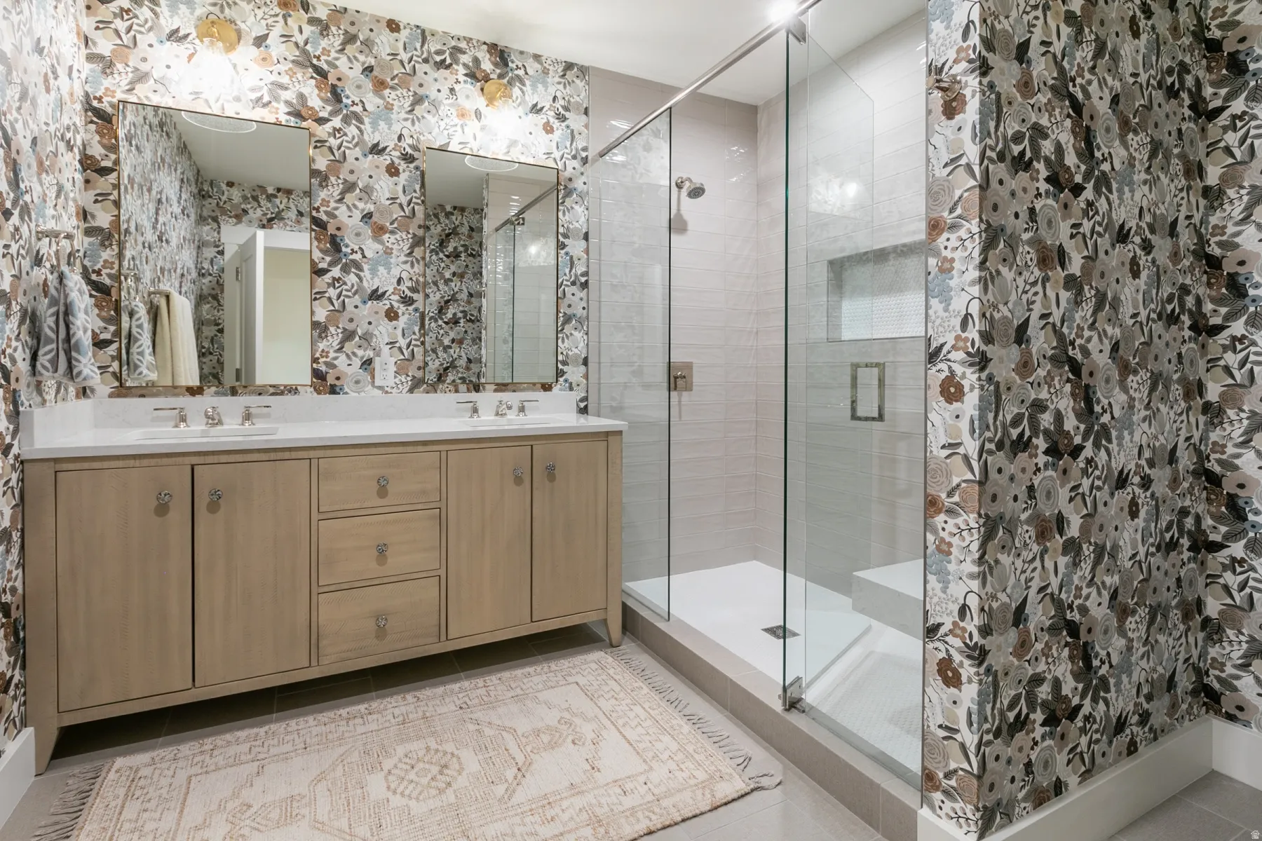 Walk-in shower with clear glass enclosure and light-toned tile surround