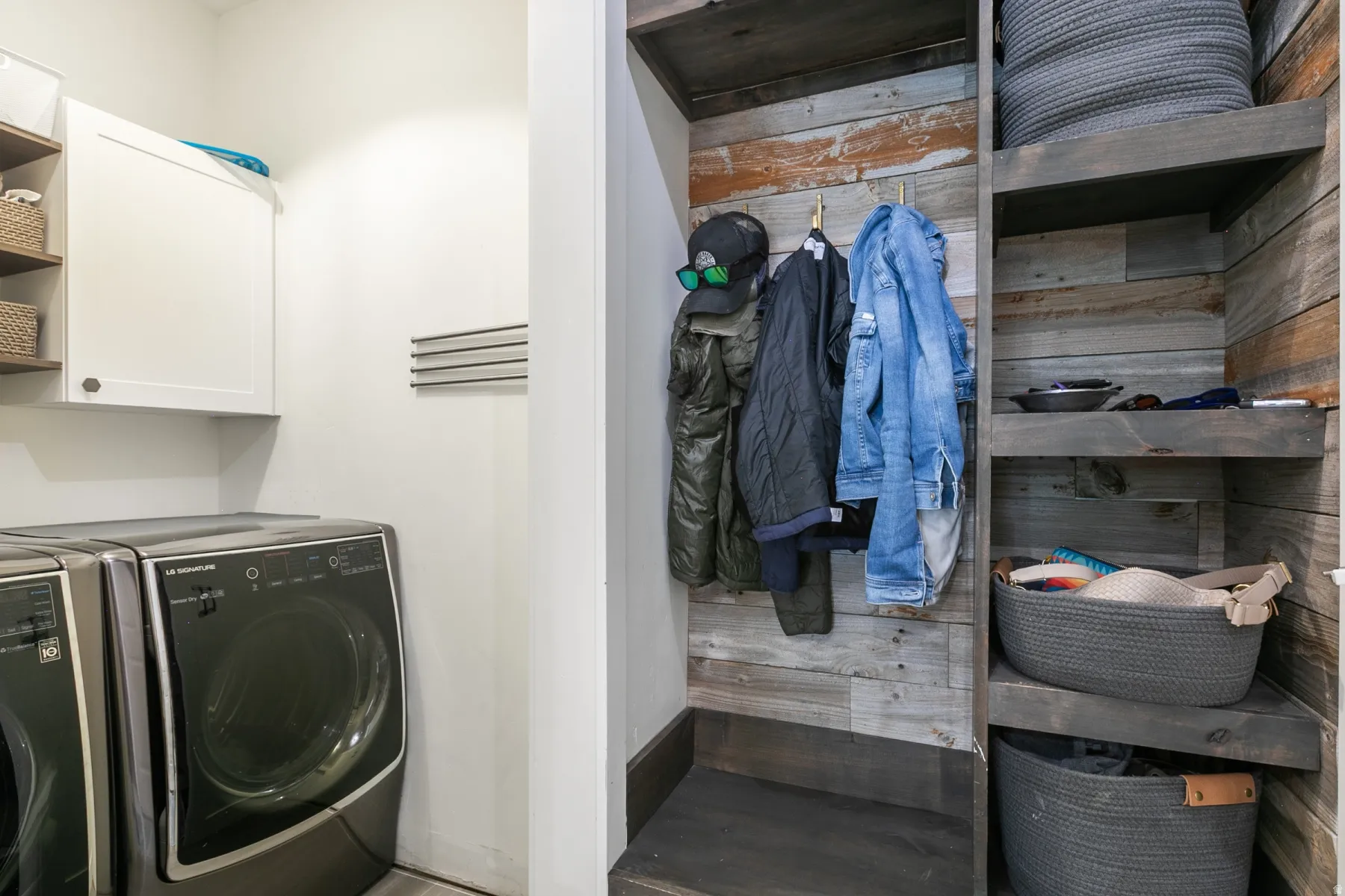 Dedicated laundry area featuring a front-load washer, upper cabinetry, and a wall-mounted drying rack