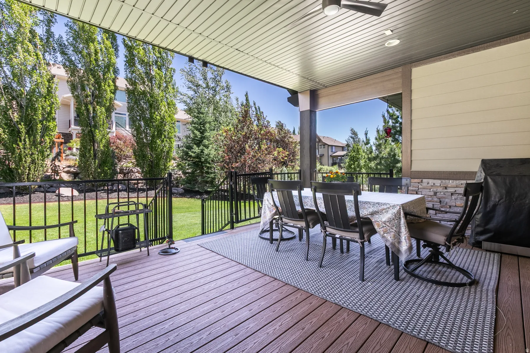 Covered deck featuring wood-finish flooring, stone accent walls, a ceiling fan, and recessed lighting