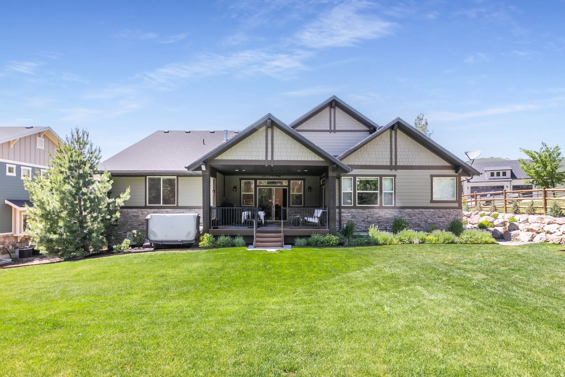 Expansive backyard with a manicured lawn, a covered patio, and a stone retaining wall