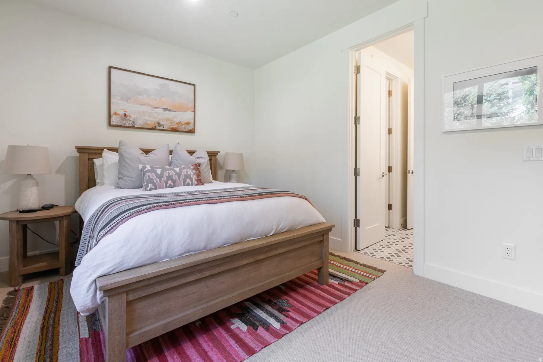Spacious room featuring a light wood-finish bed frame, neutral-toned walls, recessed lighting, and soft carpet flooring