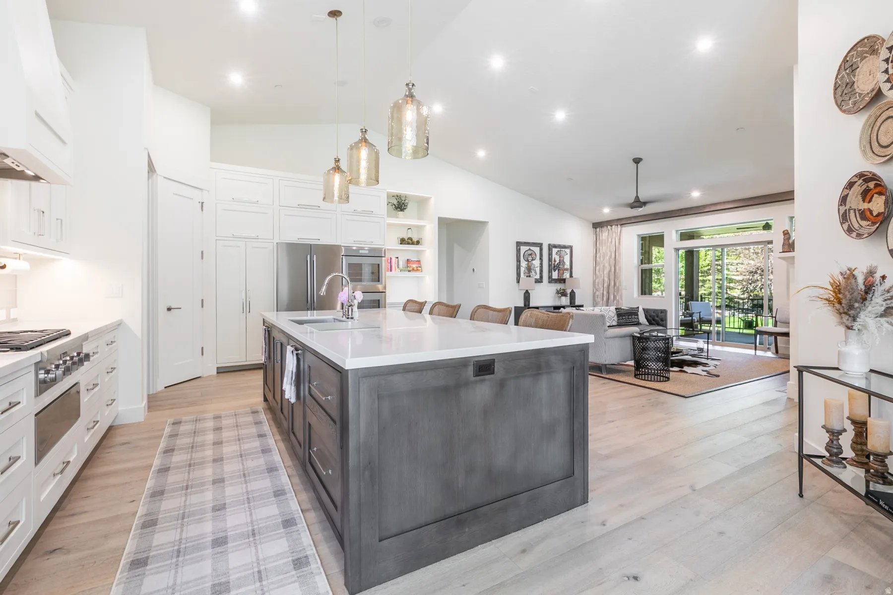 Spacious kitchen featuring a large central island with seating, stainless steel appliances, white cabinetry, and wood-finish flooring