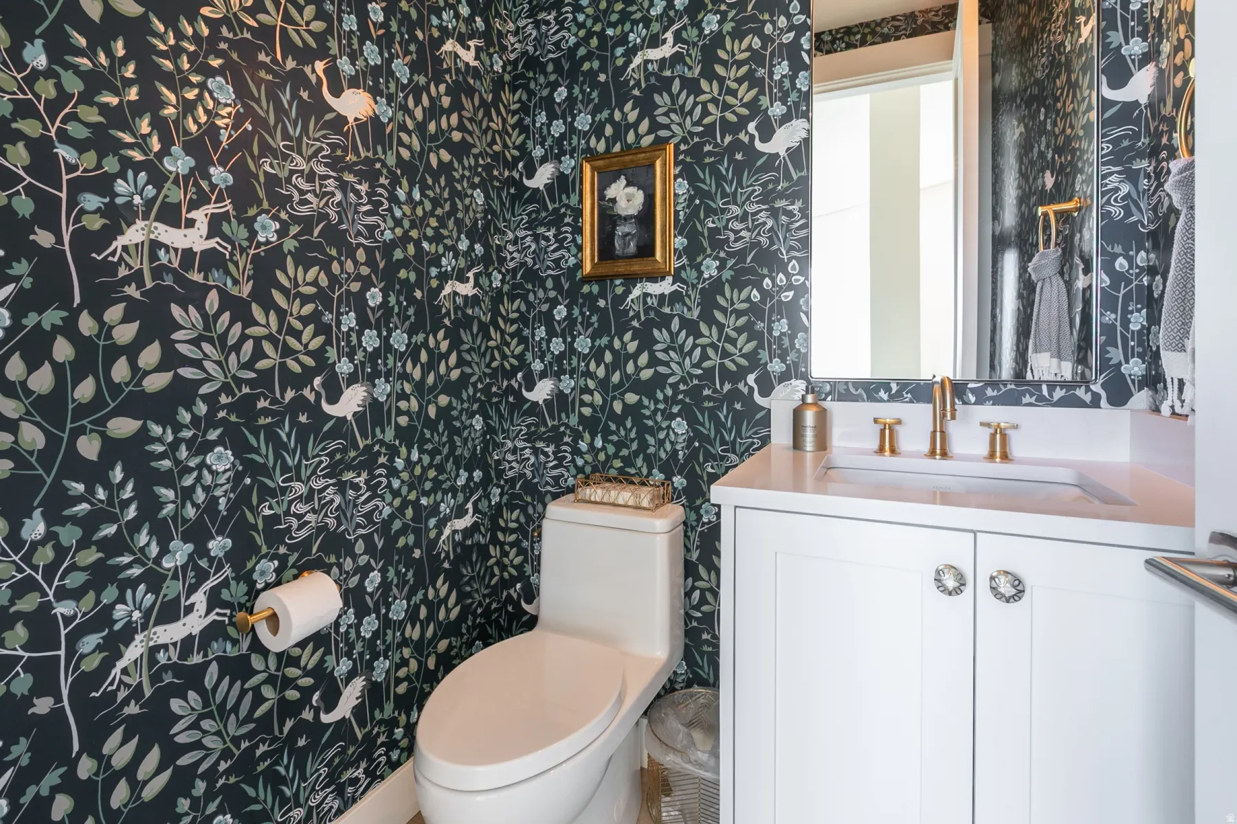 Powder room featuring botanical wallpaper with accent vanity