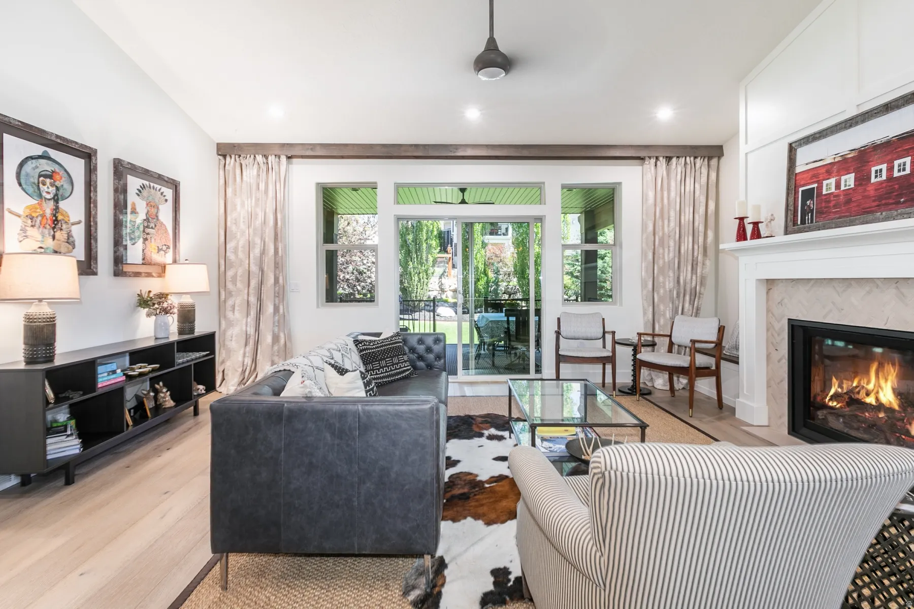 Bright living area featuring wood-finish flooring, a white mantel fireplace with a herringbone tile surround, and recessed lighting