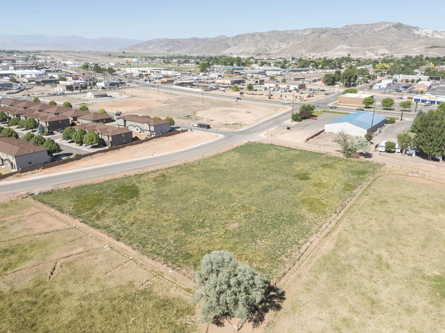 Expansive lot featuring varied terrain and natural vegetation, bordered by a paved road