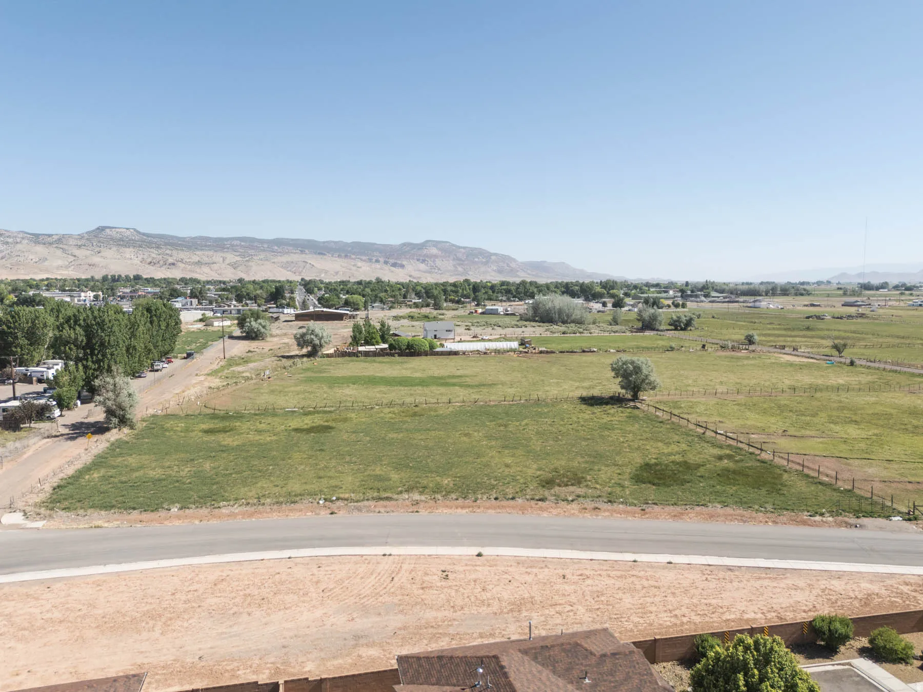 Expansive property with a paved road, mountain backdrop, and distant structures
