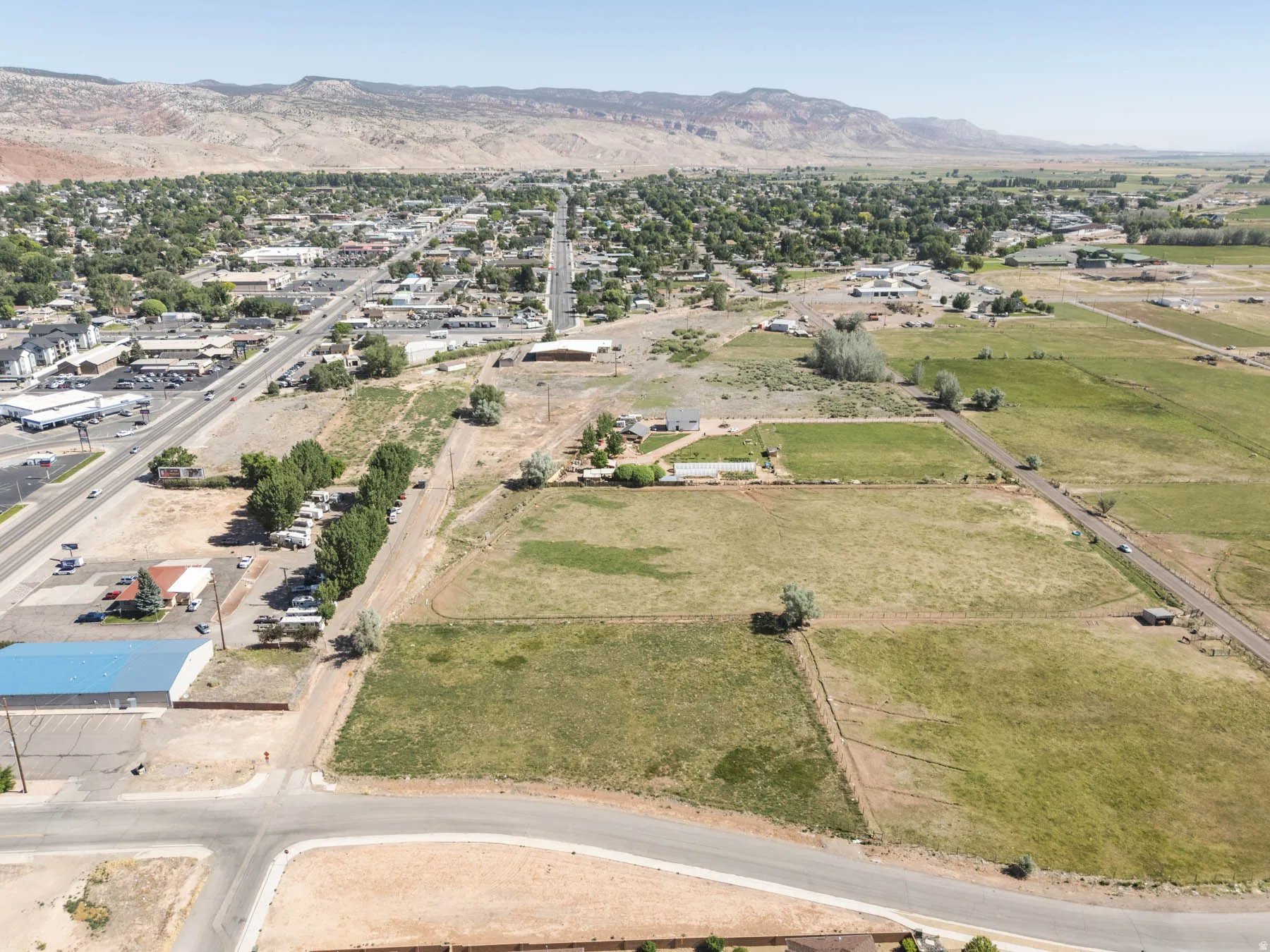 Expansive rural landscape featuring a mix of open fields, scattered residential structures, and distant mountainous terrain