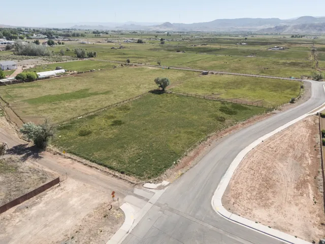 Expansive rural landscape featuring a paved street, established fencing, and distant mountains