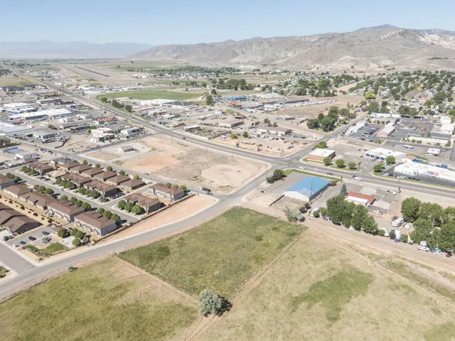 Expansive land parcel featuring existing infrastructure, surrounded by established residential developments, commercial properties, and a clear mountain backdrop