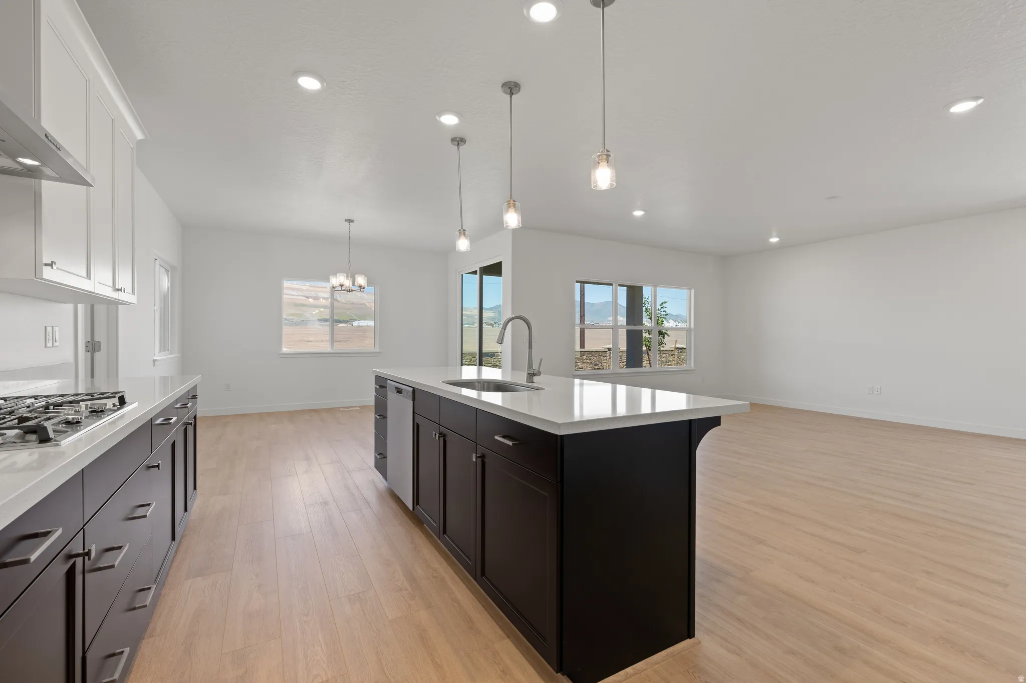 Modern kitchen featuring dark wood-finish cabinetry, light countertops, and a central island with pendant lighting