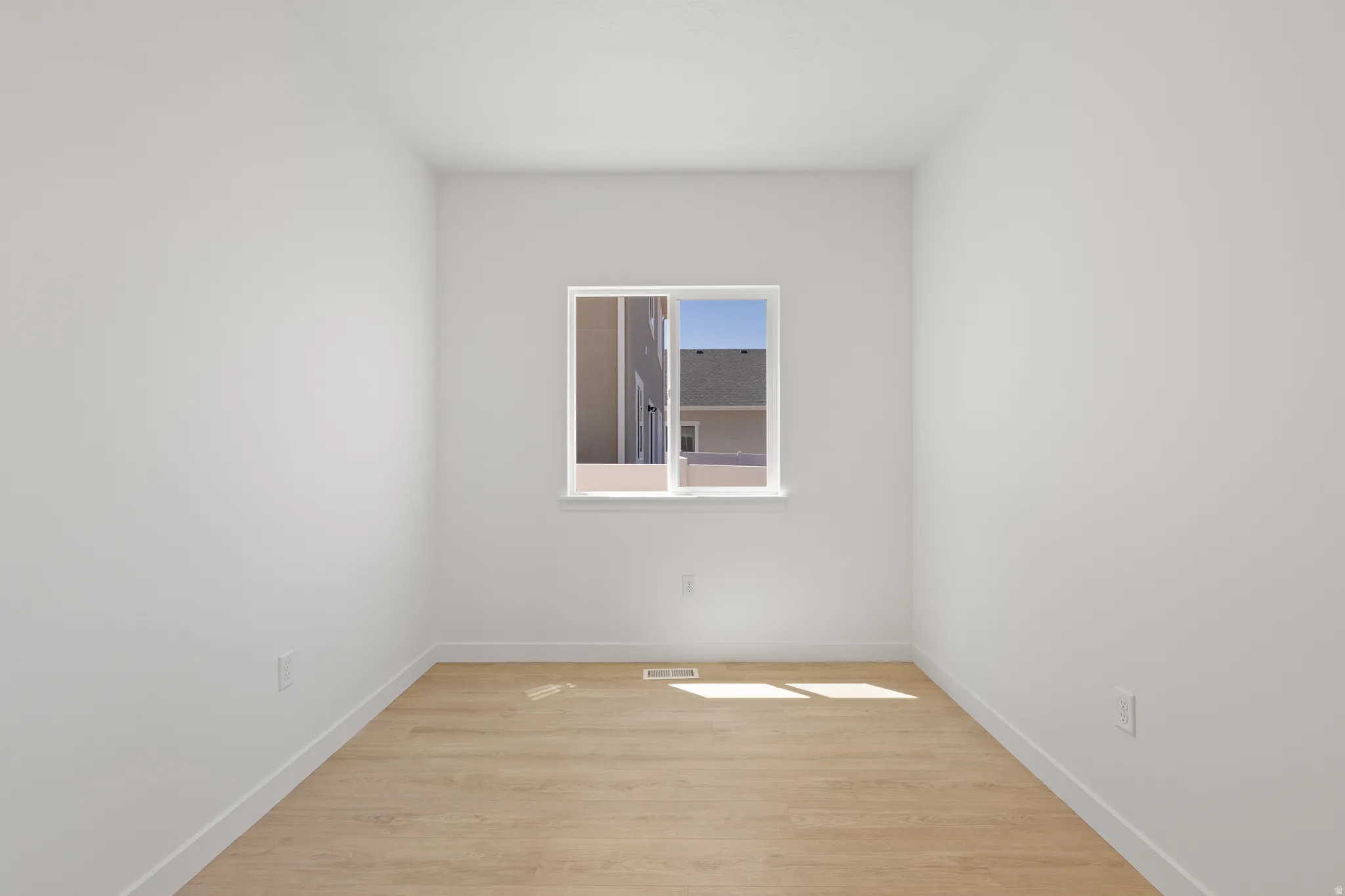 White wall finishes and wood-finish flooring with a single window