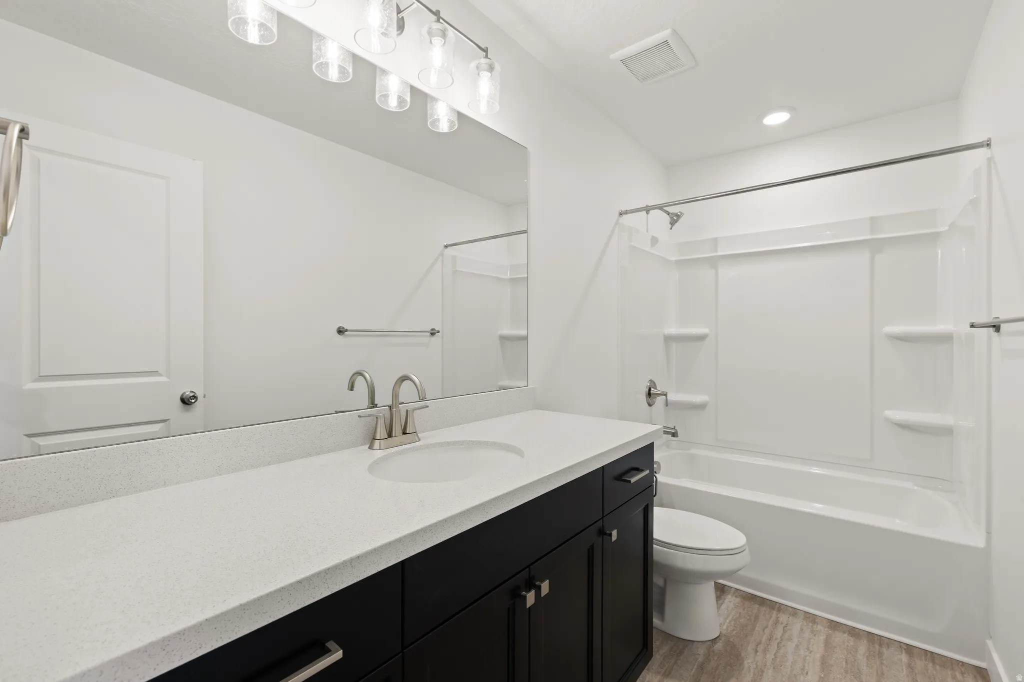 Bathroom featuring a long vanity with a light-colored countertop, dark wood-finish cabinetry, and a single undermount sink