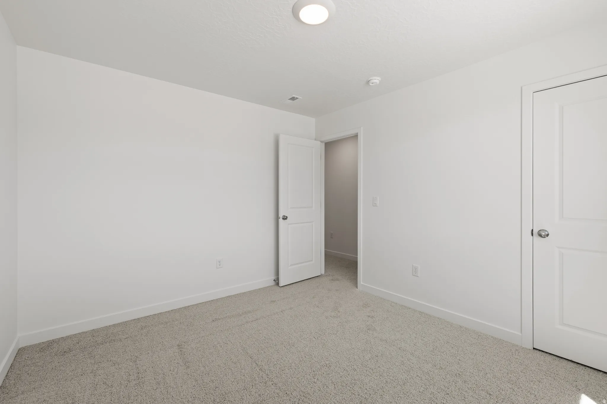 Neutral white walls with matching trim and doors, complemented by light-colored carpeting