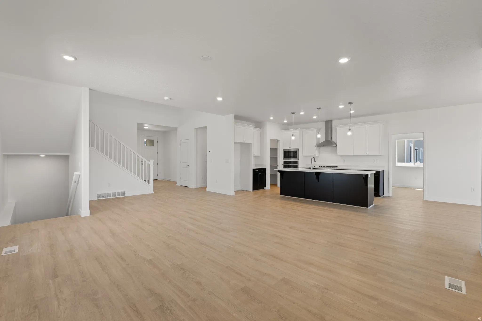 Expansive open-concept living space with wood-finish flooring