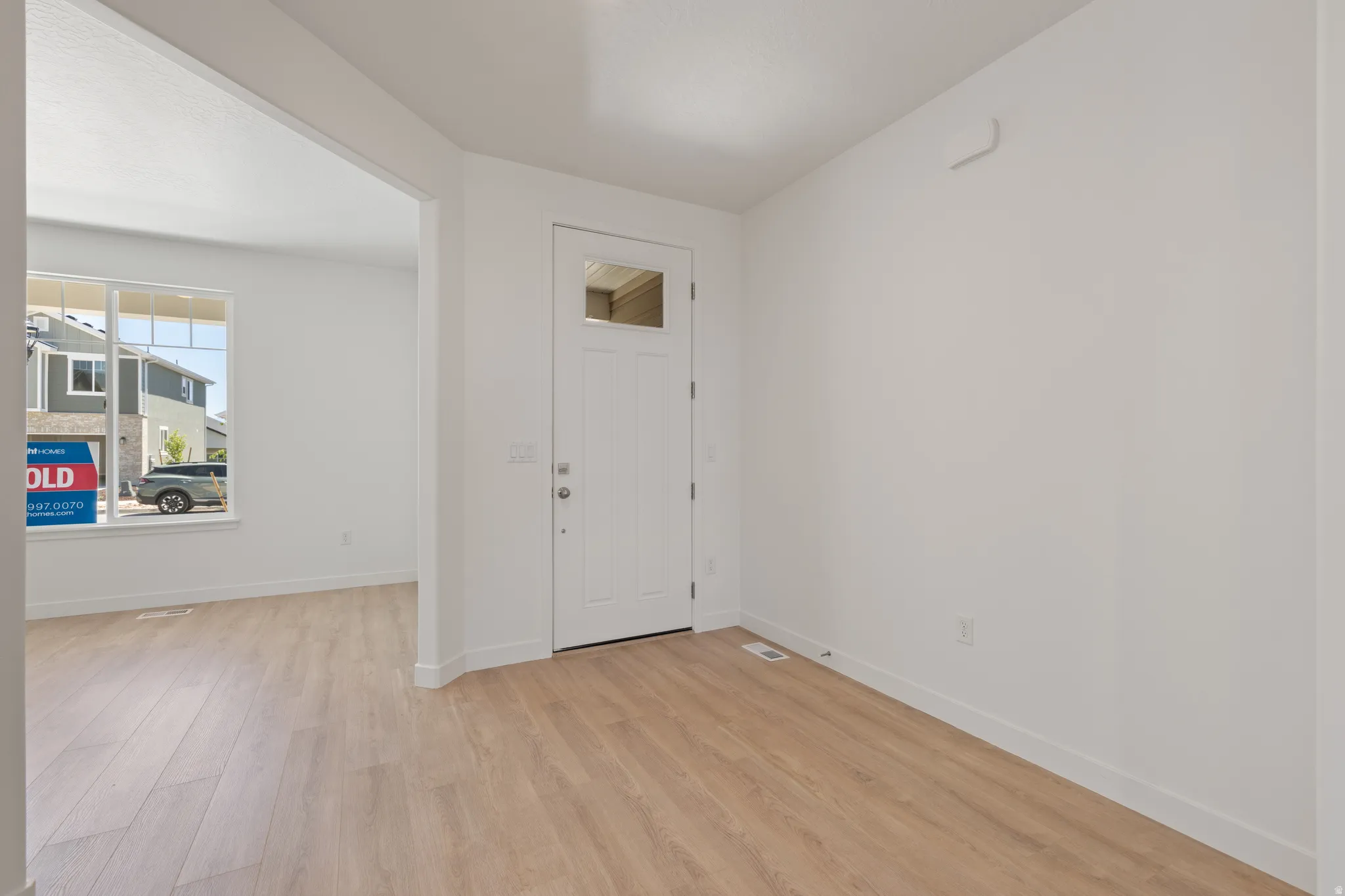 Entryway featuring a white paneled door with decorative glass, wood-finish flooring, and crisp white walls