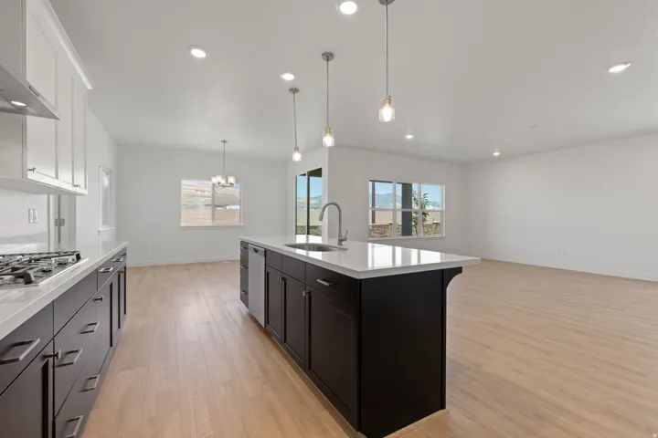Modern kitchen featuring dark wood-finish cabinetry, light countertops, and a central island with pendant lighting