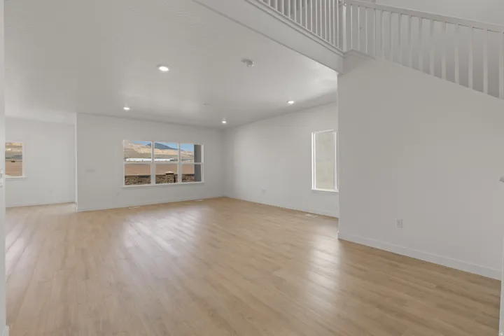 Spacious open-concept interior featuring light wood-finish flooring and crisp white walls