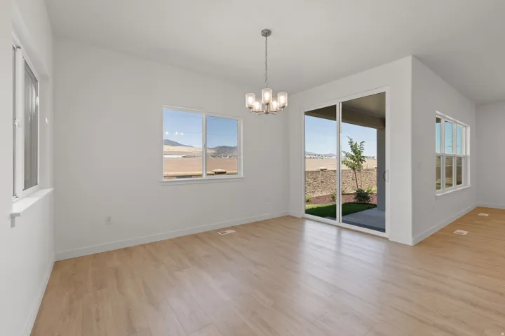 Spacious room featuring light wood-finish flooring and ample natural light from multiple windows and a sliding glass door