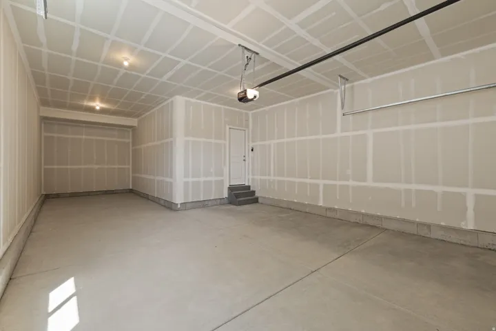 Spacious garage featuring a concrete floor, exposed drywall walls, and a ceiling with two recessed light fixtures