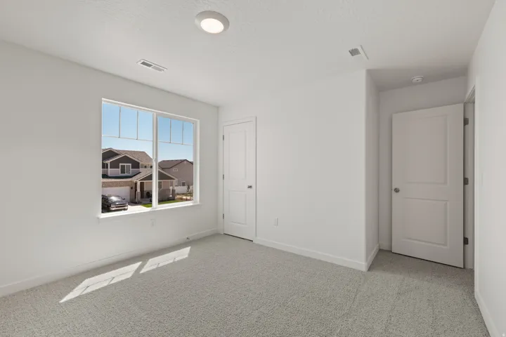 Bright interior space featuring a large window, light gray carpeting, crisp white walls, and a recessed ceiling light