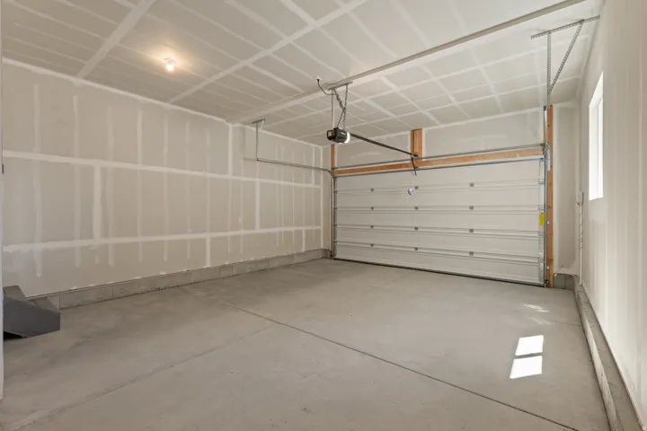 Spacious two-car garage featuring a concrete floor, an overhead garage door, built-in garage door opener, and a single window for natural light