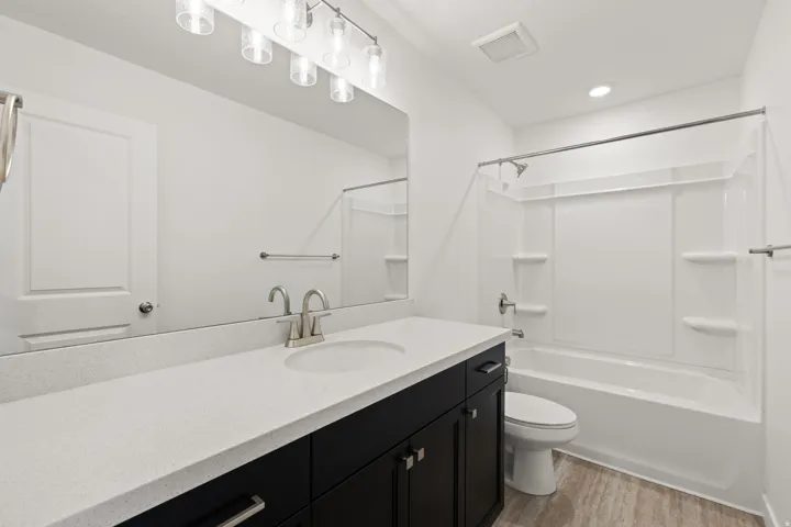 Bathroom featuring a long vanity with a light-colored countertop, dark wood-finish cabinetry, and a single undermount sink