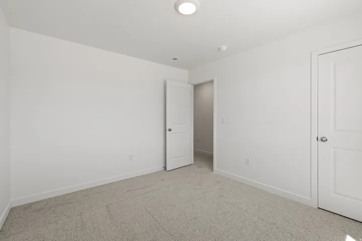 Neutral white walls with matching trim and doors, complemented by light-colored carpeting