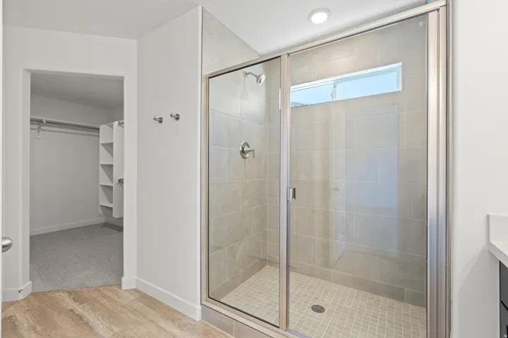 Glass-enclosed shower with a transom window, tiled walls, and a mosaic-tiled floor
