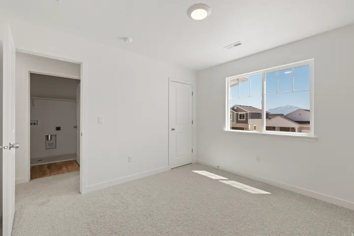 Bright room featuring light-colored carpeting, a large window, and crisp white walls