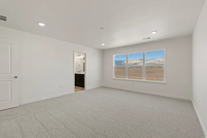 Expansive room featuring multiple windows framing a mountain backdrop, neutral carpeting, recessed lighting, and a white interior door