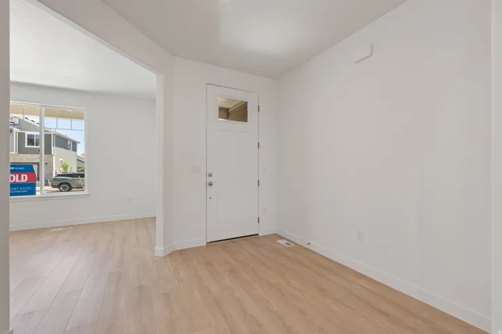 Entryway featuring a white paneled door with decorative glass, wood-finish flooring, and crisp white walls