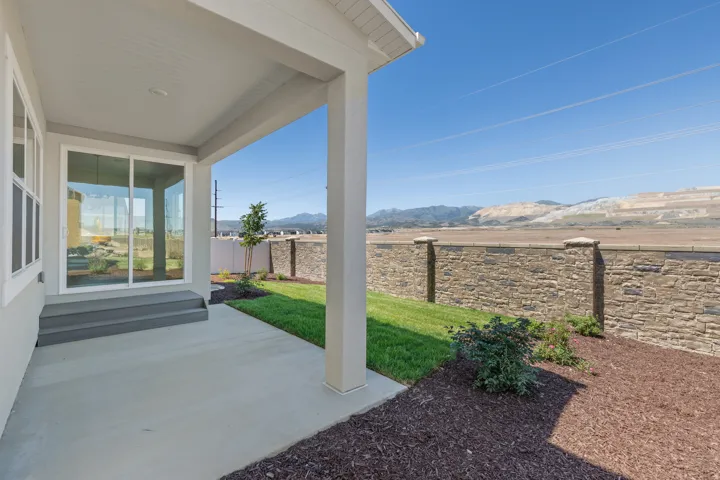 Covered patio with concrete flooring, framed by a stone wall
