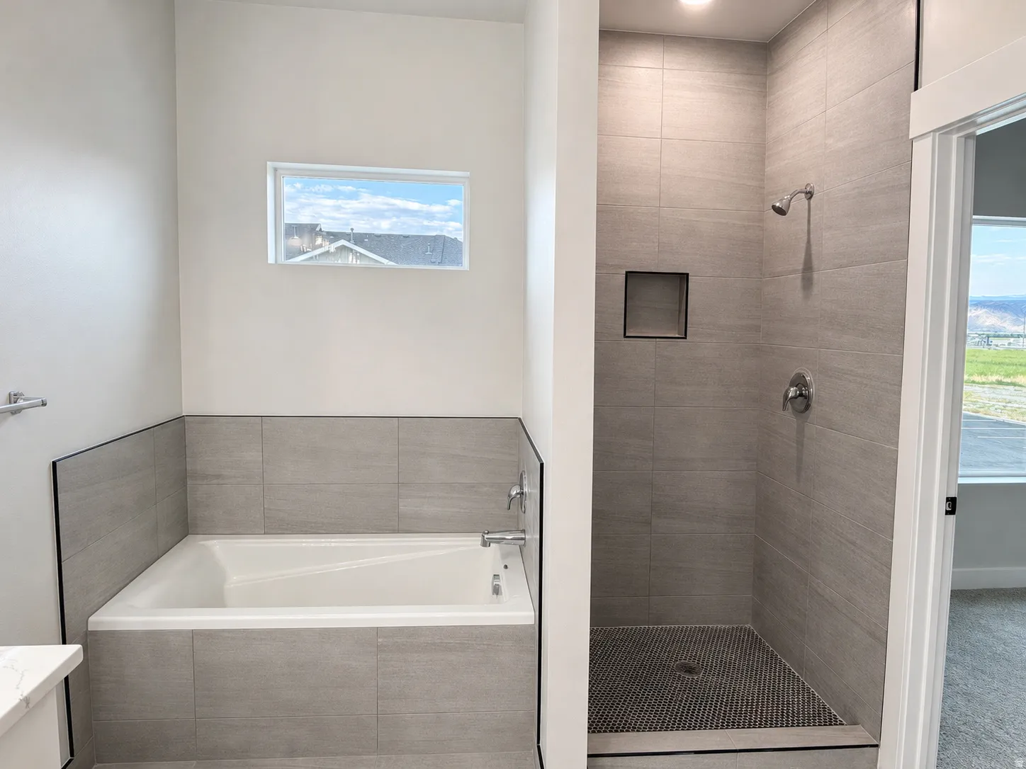 Modern bathroom featuring a tiled soaking tub and a walk-in shower with a recessed niche