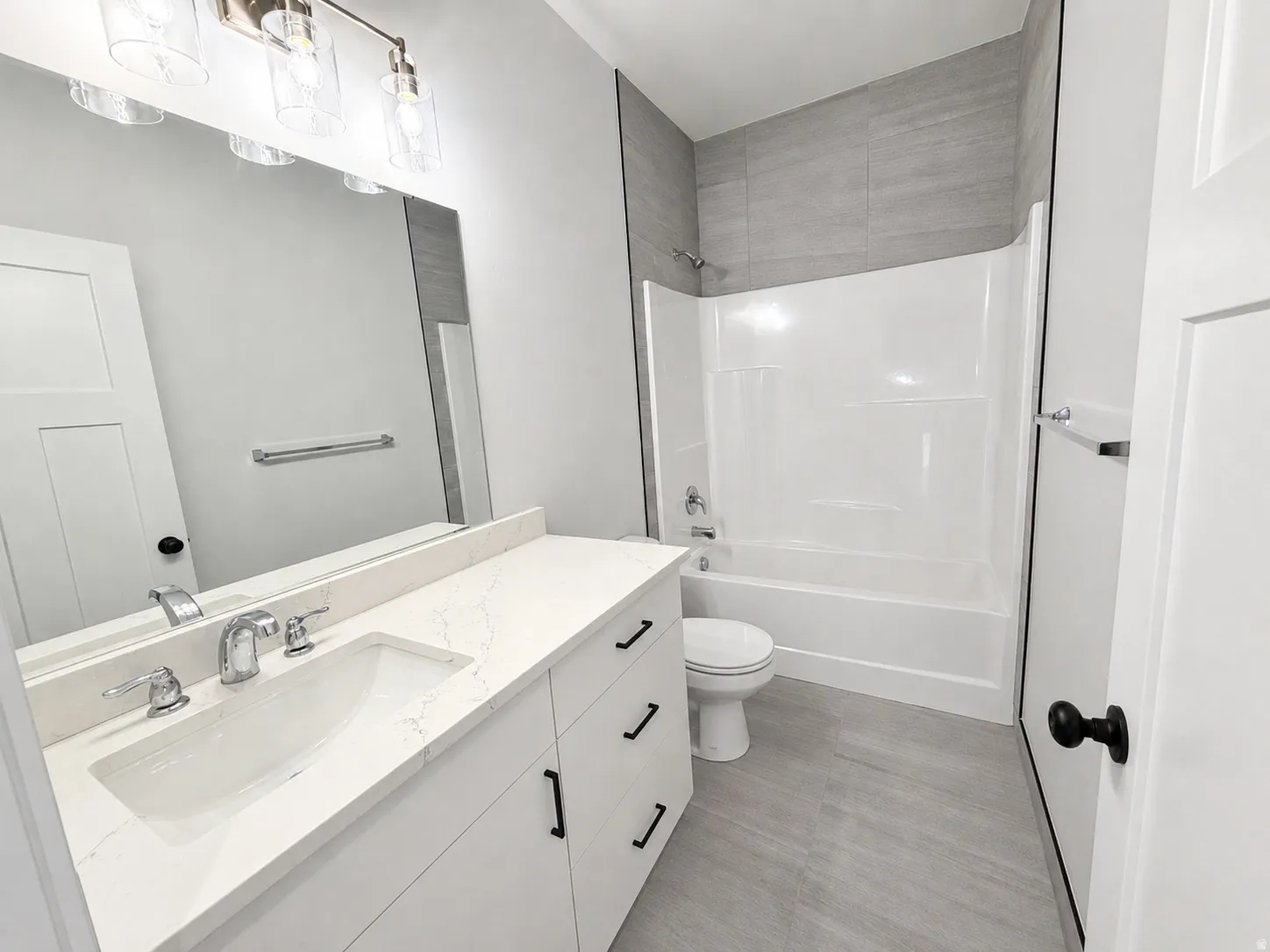 Full bathroom featuring a white vanity with a rectangular undermount sink, a quartz countertop, and a chrome faucet