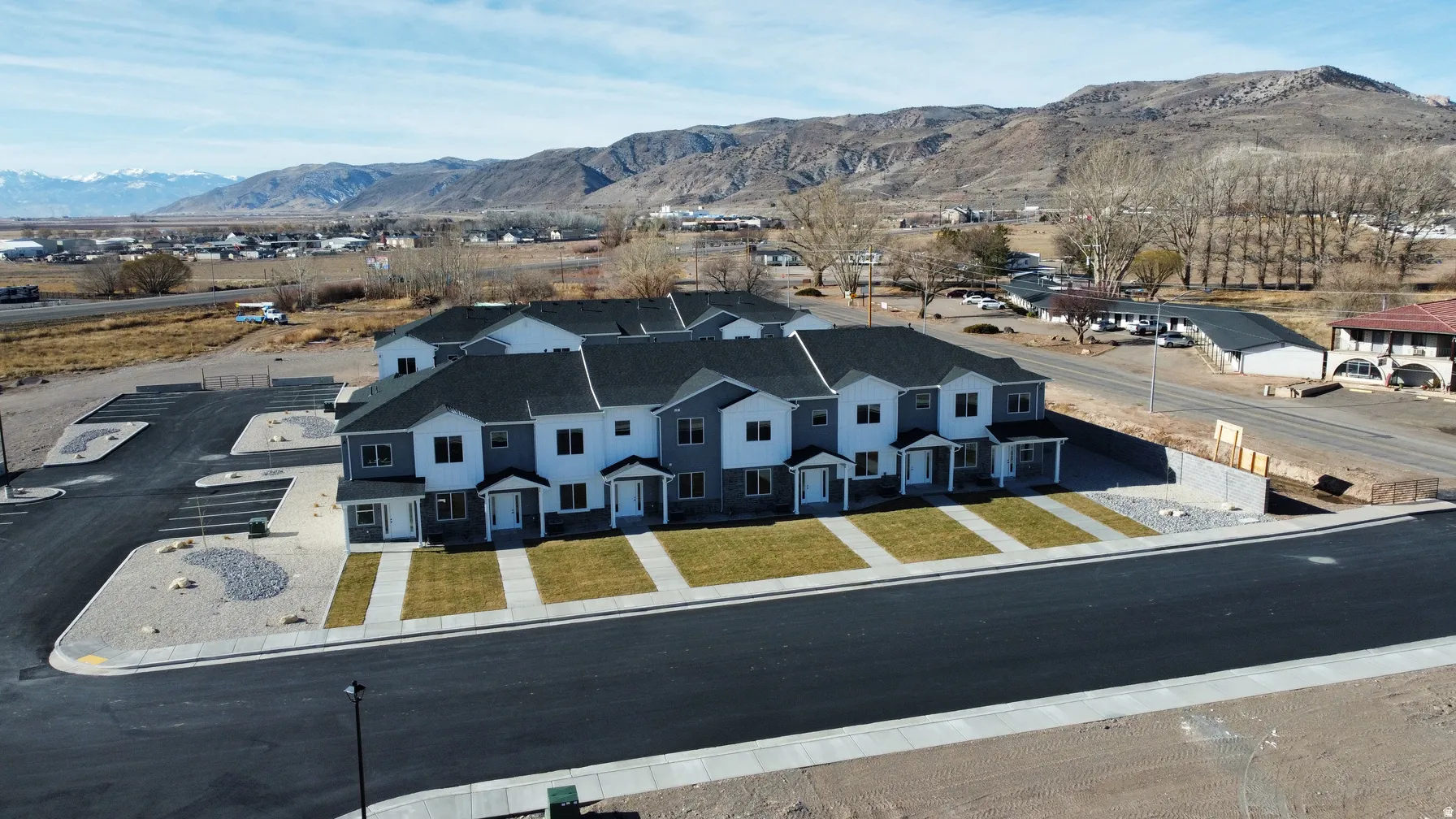 Contemporary multi-unit property featuring a dark gray roofline, light gray siding, white trim, and individual front porches