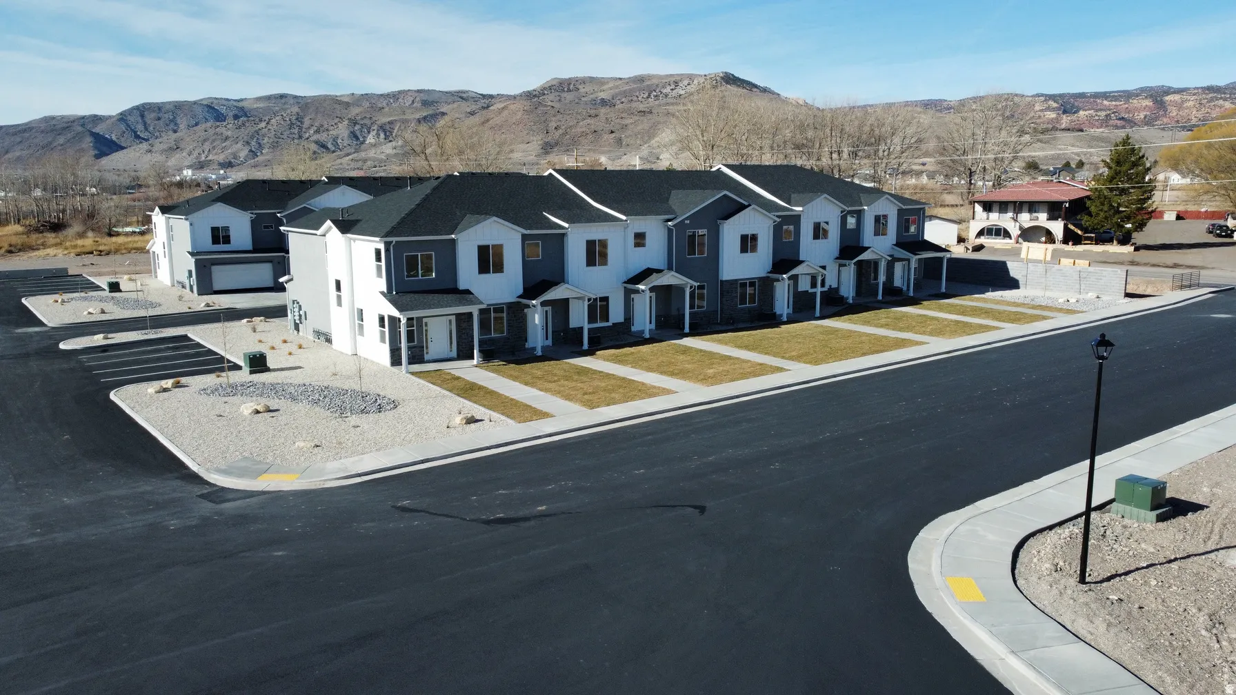 Modern townhome complex featuring a gray and white exterior with dark shingle roofing
