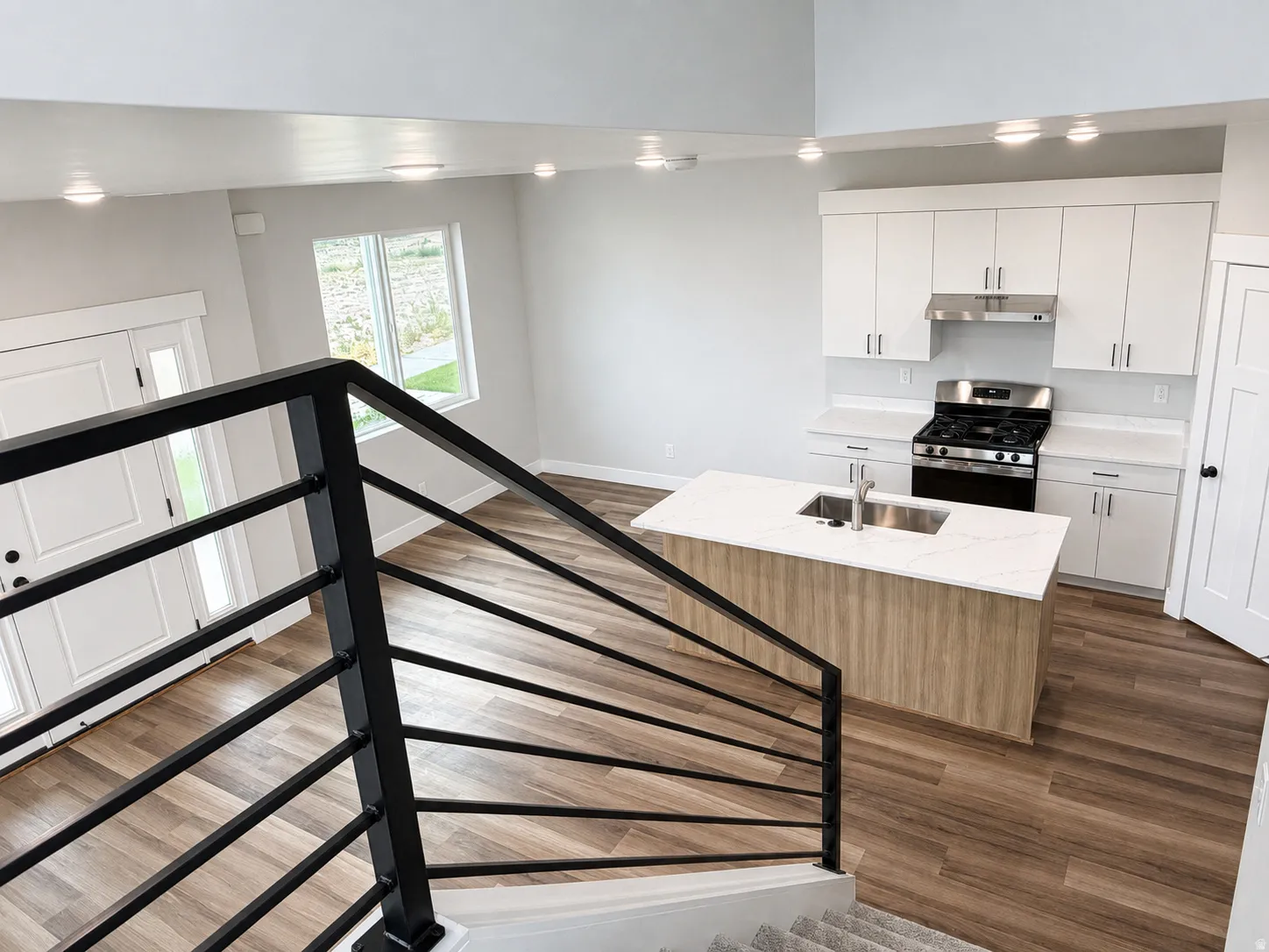 Open-concept living space featuring a modern kitchen with white cabinetry, stainless steel appliances, and an island with an integrated sink
