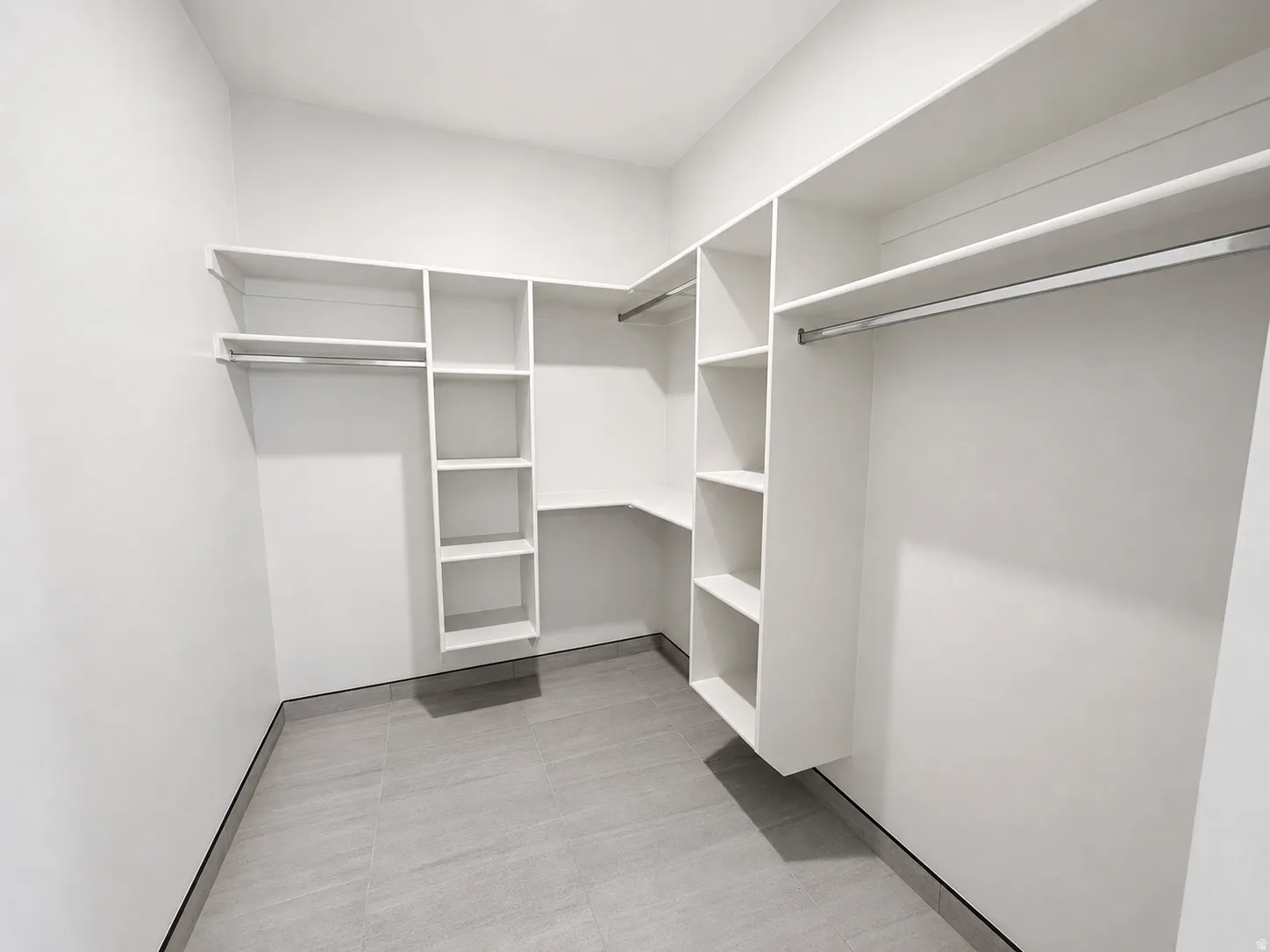 Expansive custom closet featuring white built-in shelving, integrated hanging rods, and tile flooring